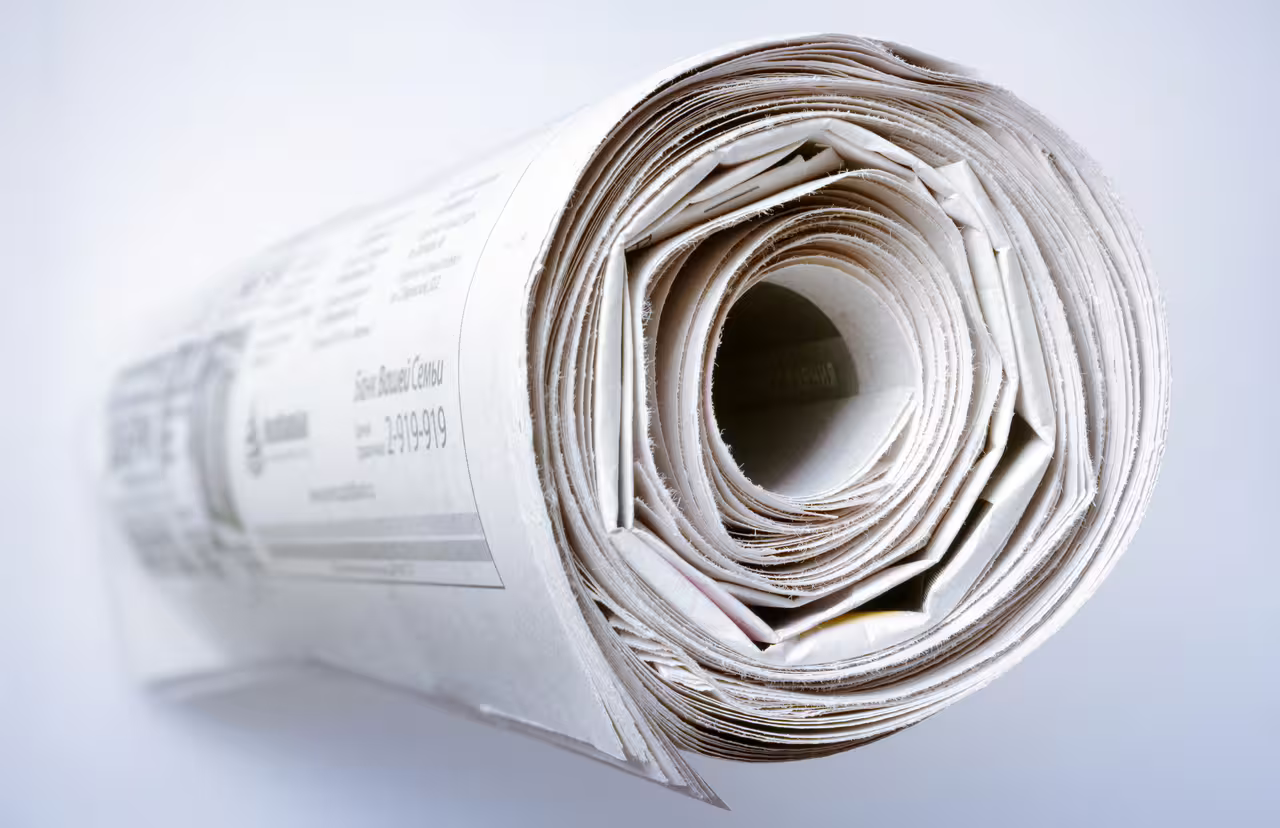 Eine gerollte Zeitung von der Seite mit hellem Hintergrund